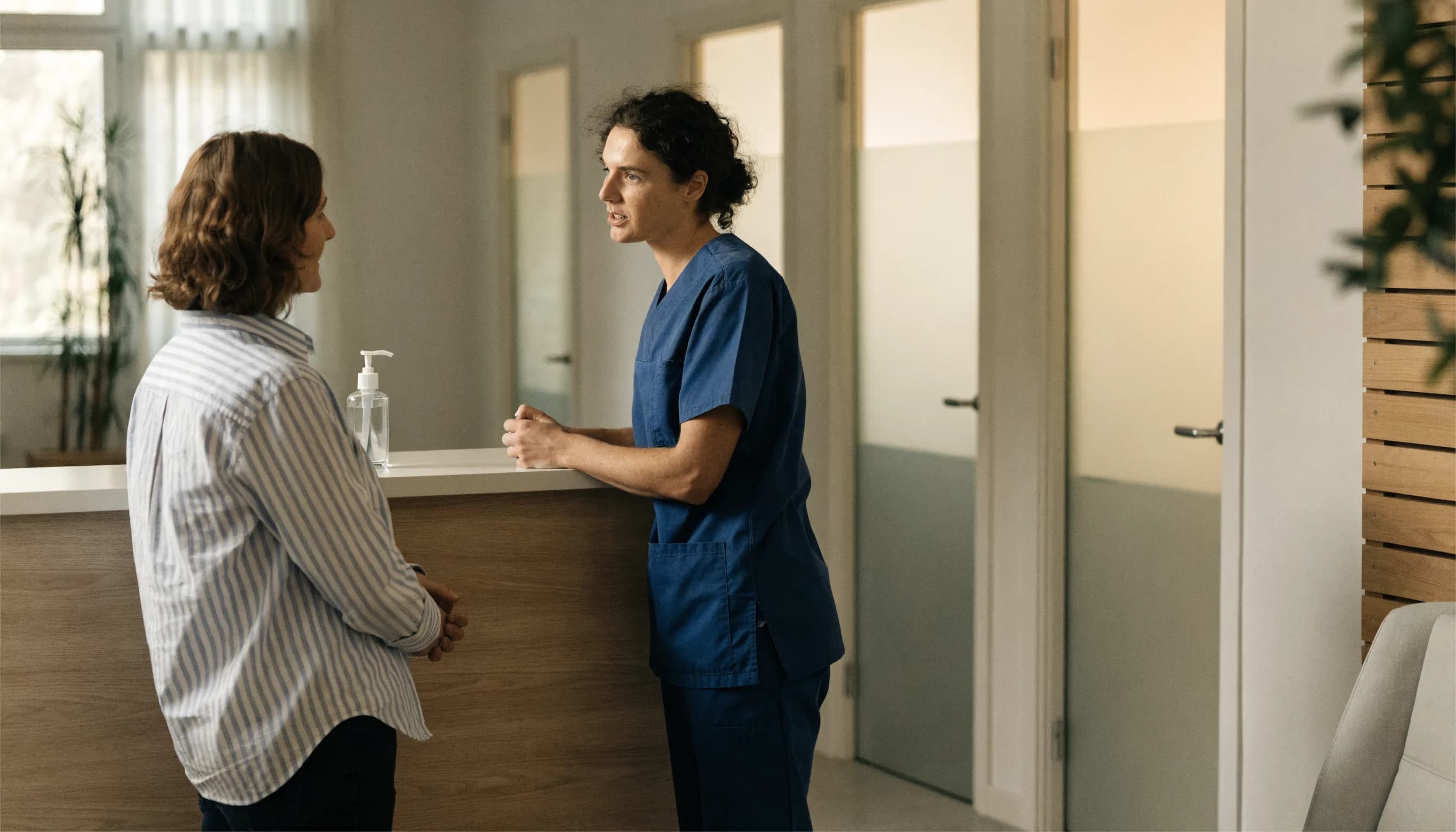 Healthcare practice staff member guiding a visitor at a calm modern reception area